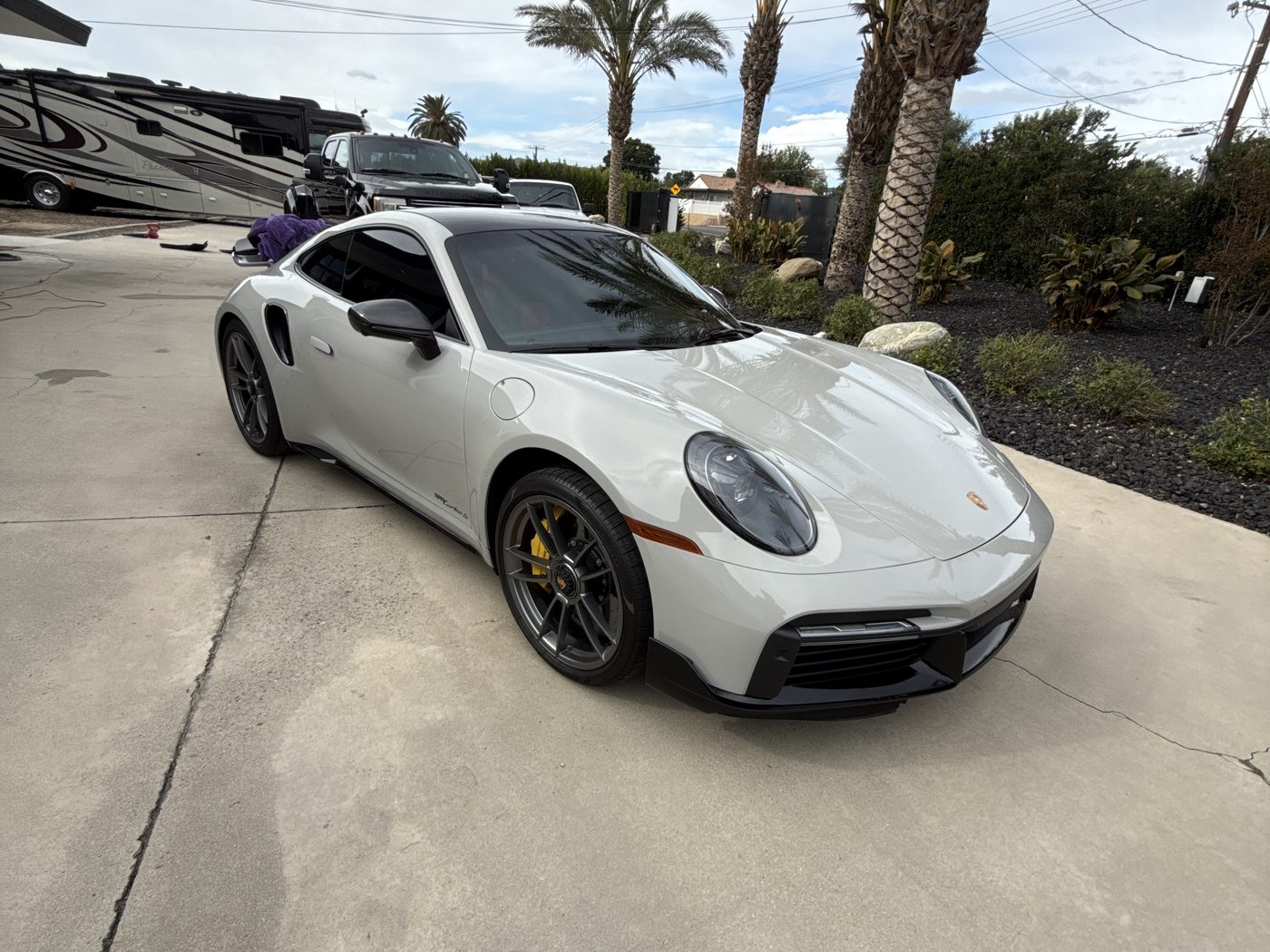 Gray Porsche 911 Turbo S with a deep, glossy ceramic-coated finish in a driveway