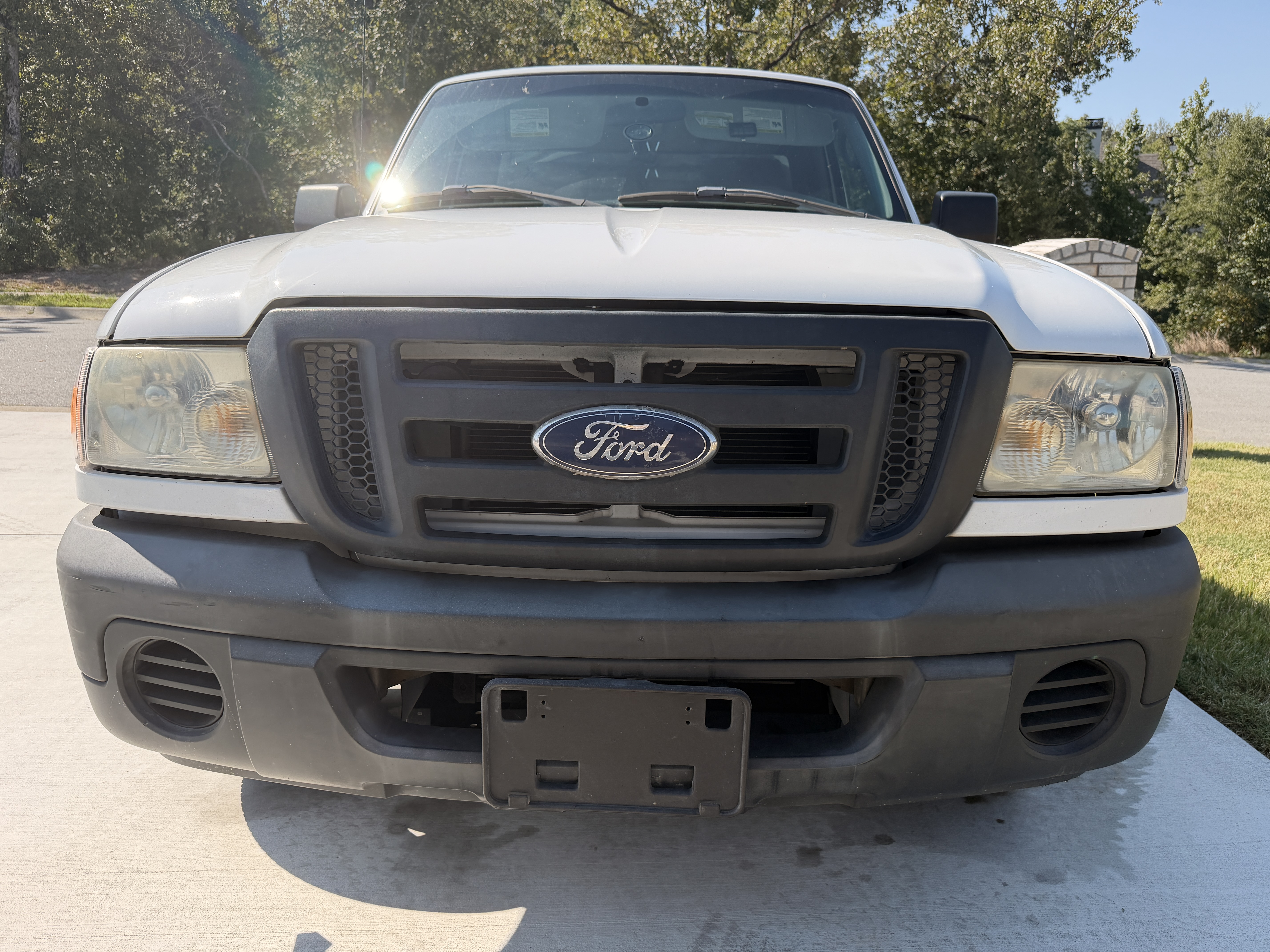 Ford truck with faded gray front bumper and grille trim before restoration