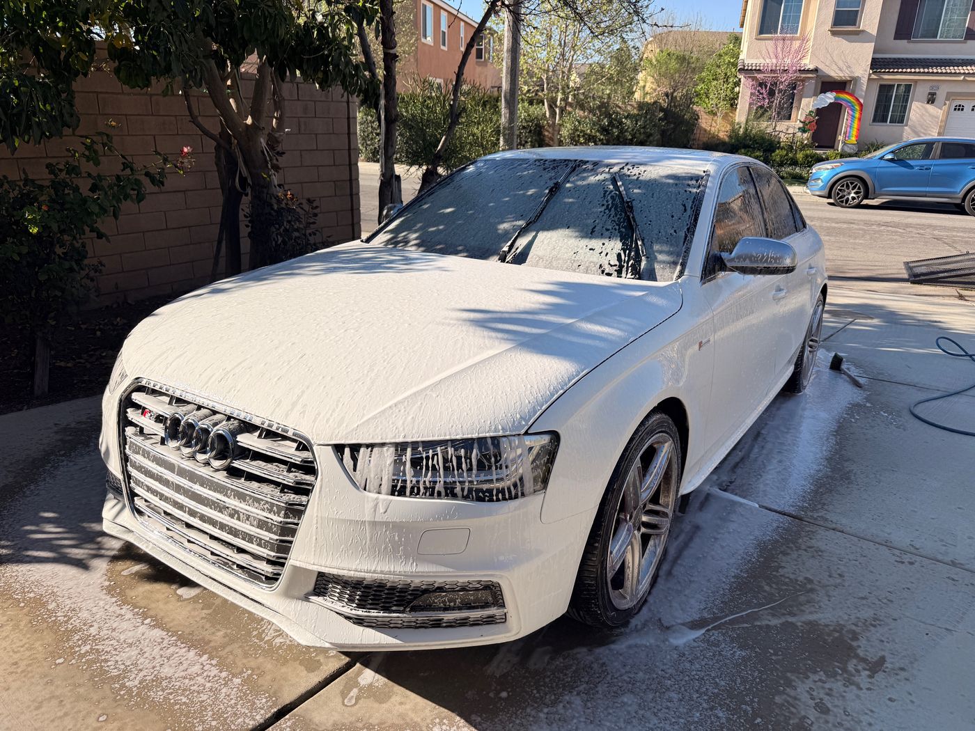 White Audi sedan covered in thick snow foam during a wash
